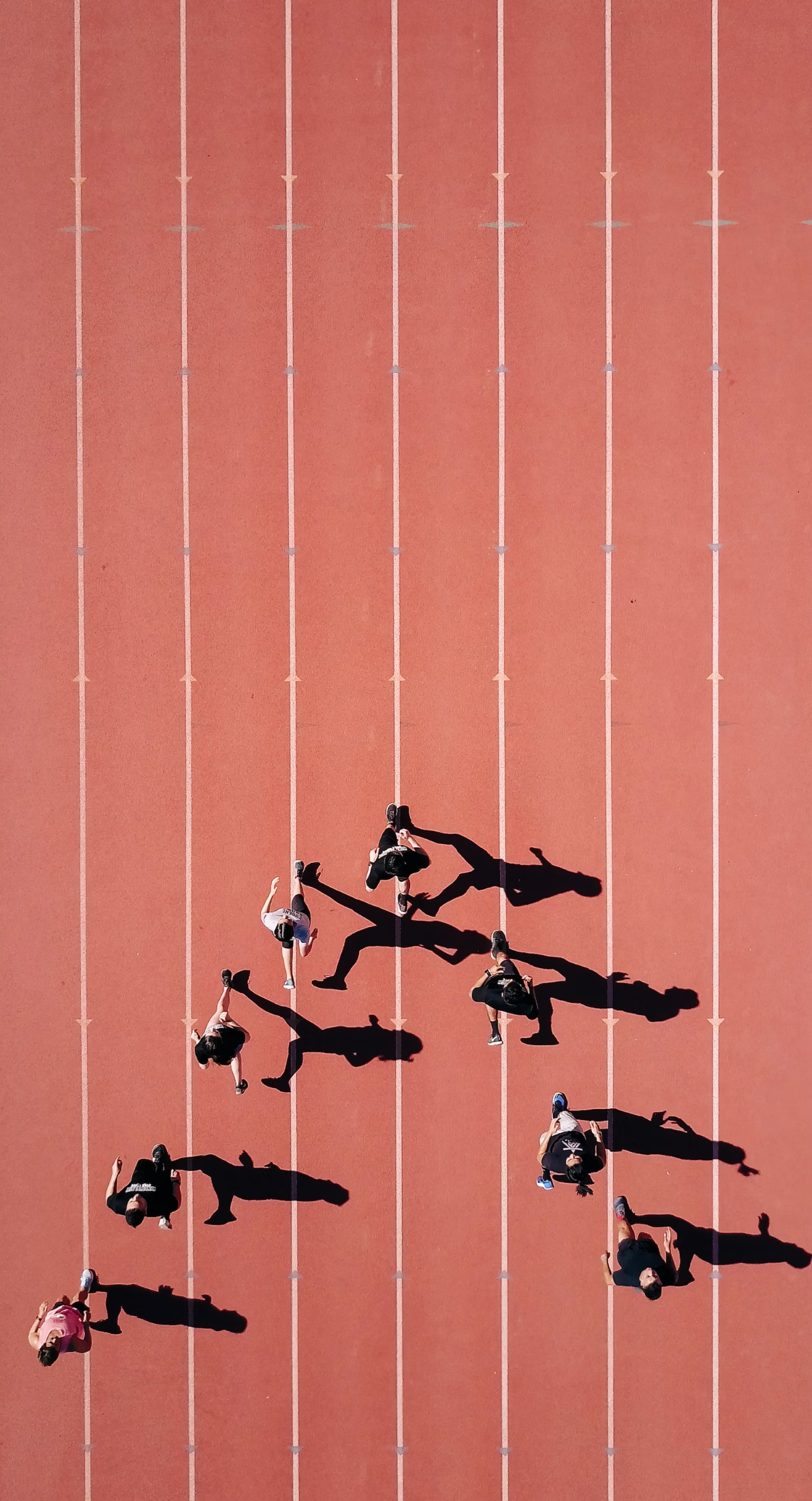 8 people running in an arrow formation on a track