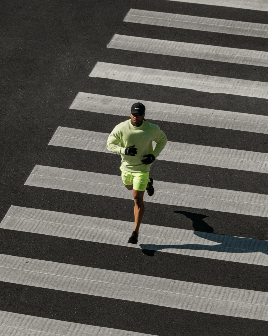 man running across a zebra crossing