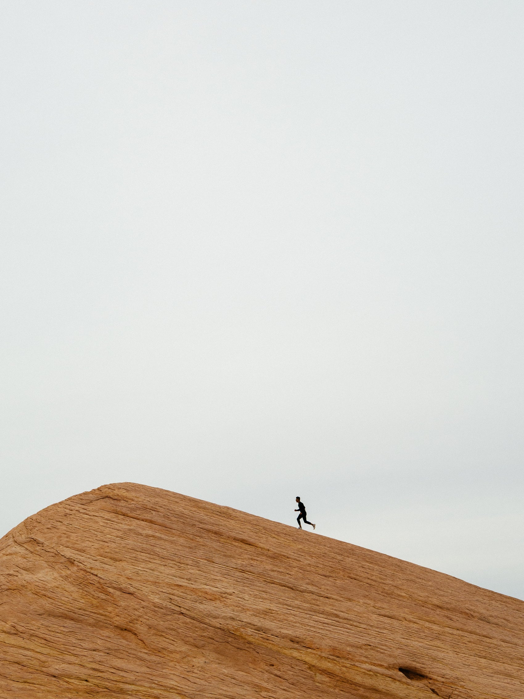man running up a steep sand dune